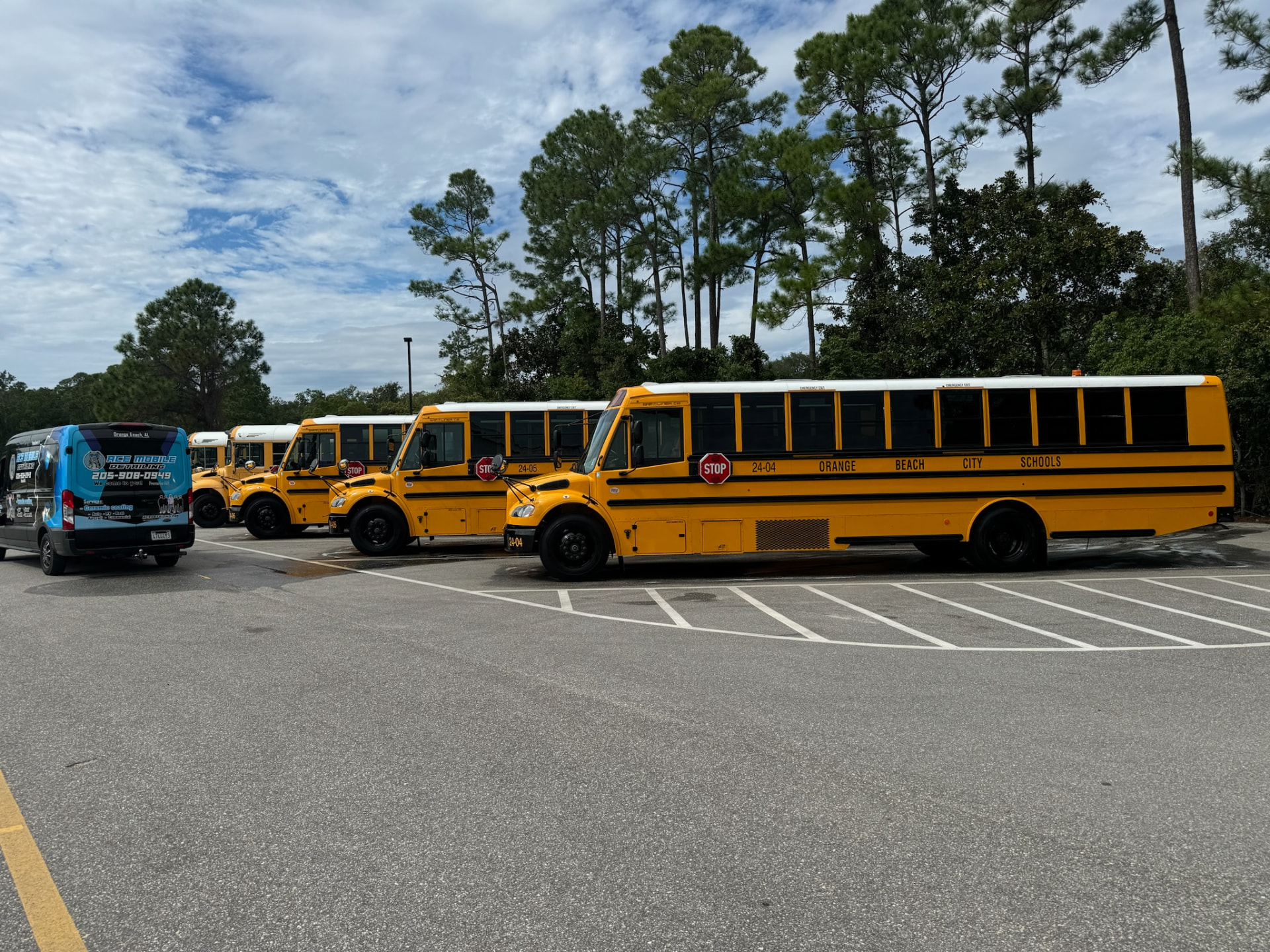 Ace Mobile Detailing service van beside a fleet of Orange Beach school buses