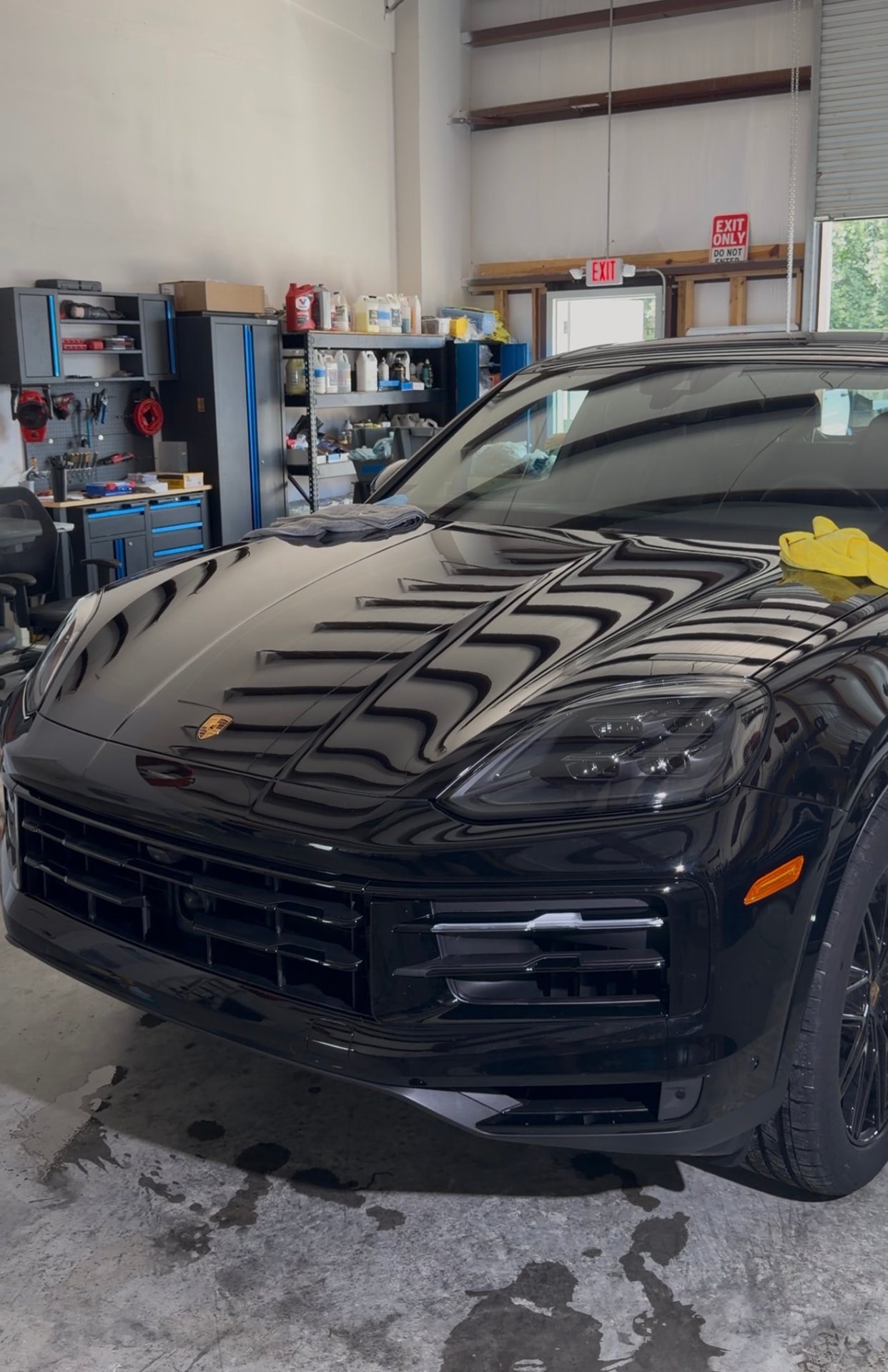 Black Porsche Cayenne with a deep glossy finish inside the Ace shop after ceramic coating