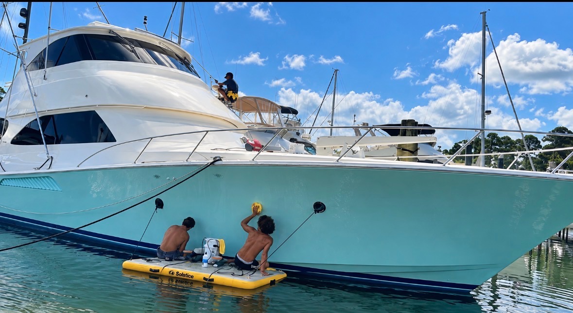 Ace crew polishing a sportfish hull from the water